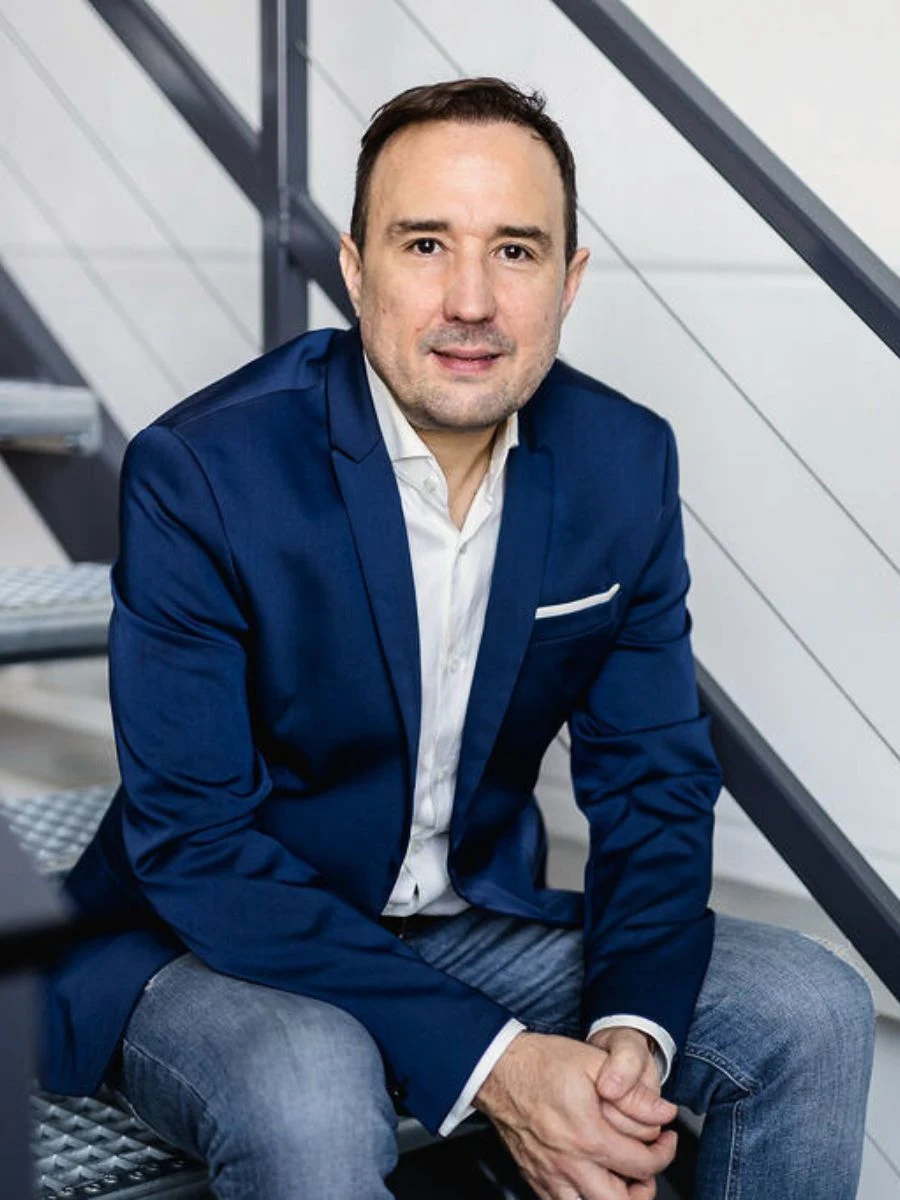 Christian Gottschling sitzt im blauen Sakko neben einer Treppe.